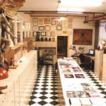 Interior of a colorful puppet museum with display cases, various puppets hanging from the ceiling, and framed pictures on the walls.
