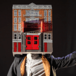 A person wearing a mask with a house on it.