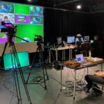 A group of people sitting in front of a green screen.
