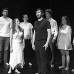 A black and white photo of a group of people standing on stage.