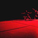 A group of dancers on a stage in a dark room.