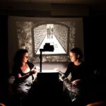 Two women watching a projected story.