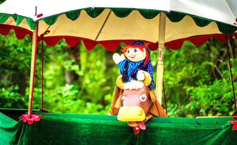 A stuffed animal riding a horse under an umbrella.