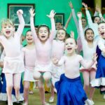 A group of children are dancing in a ballet class.