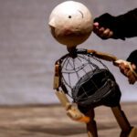 A puppet with a large head is being manipulated.