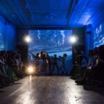 A group of people watching a fashion show on a stage.