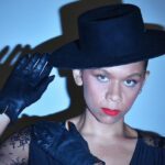 A woman wearing a black hat and gloves.