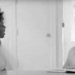Two women sitting at a table talking to each other.