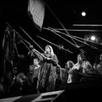 A black and white photo of a group of people holding sticks.