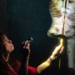 Woman holding feather duster with flashlight.